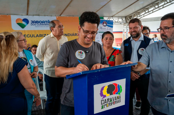 Homem assinando um documento. 