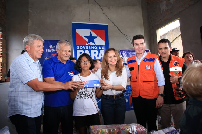 Grupo de pessoas em pé sorrindo para o fotográfo. 